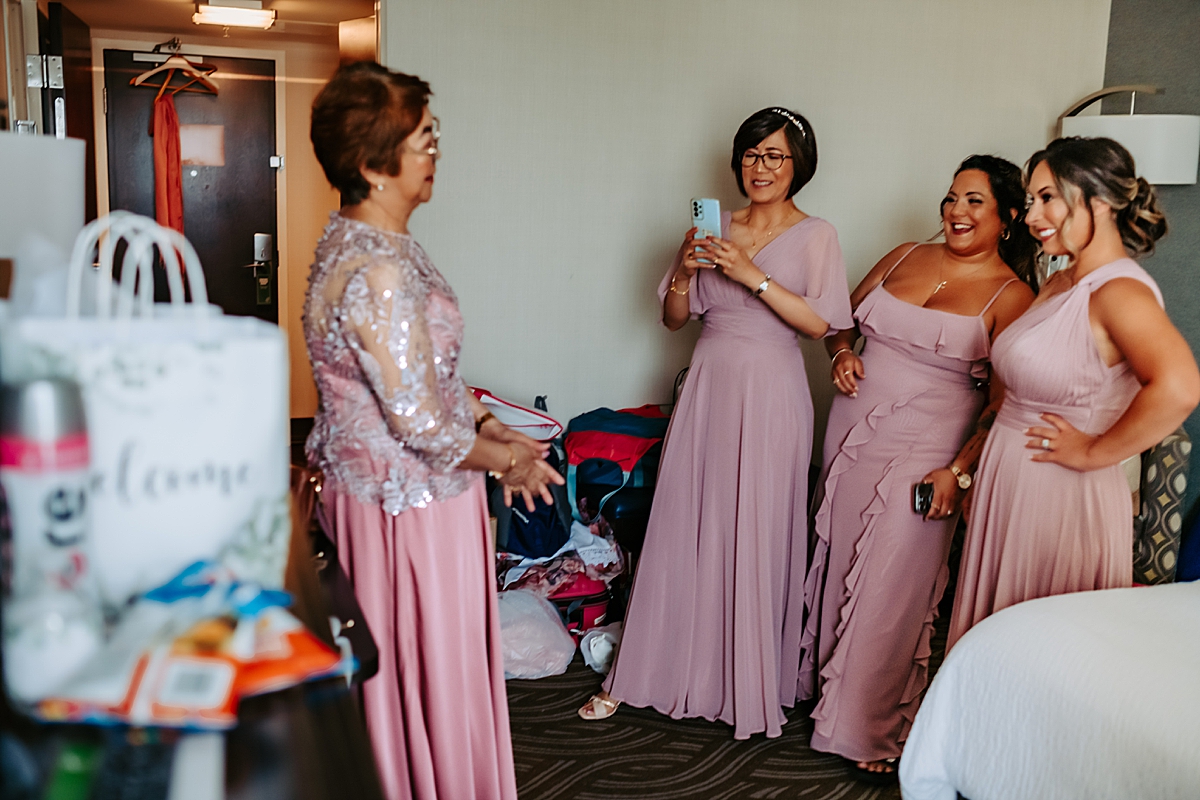 bridesmaids taking picture of bride's mother in hotel room