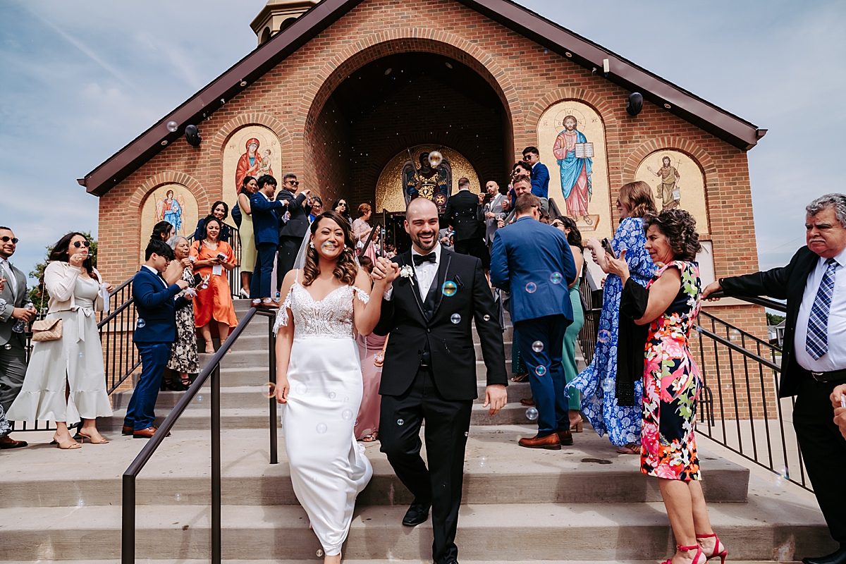 bride and groom walking down steps at Archangel Michael Greek Orthodox Church in Campbell OH