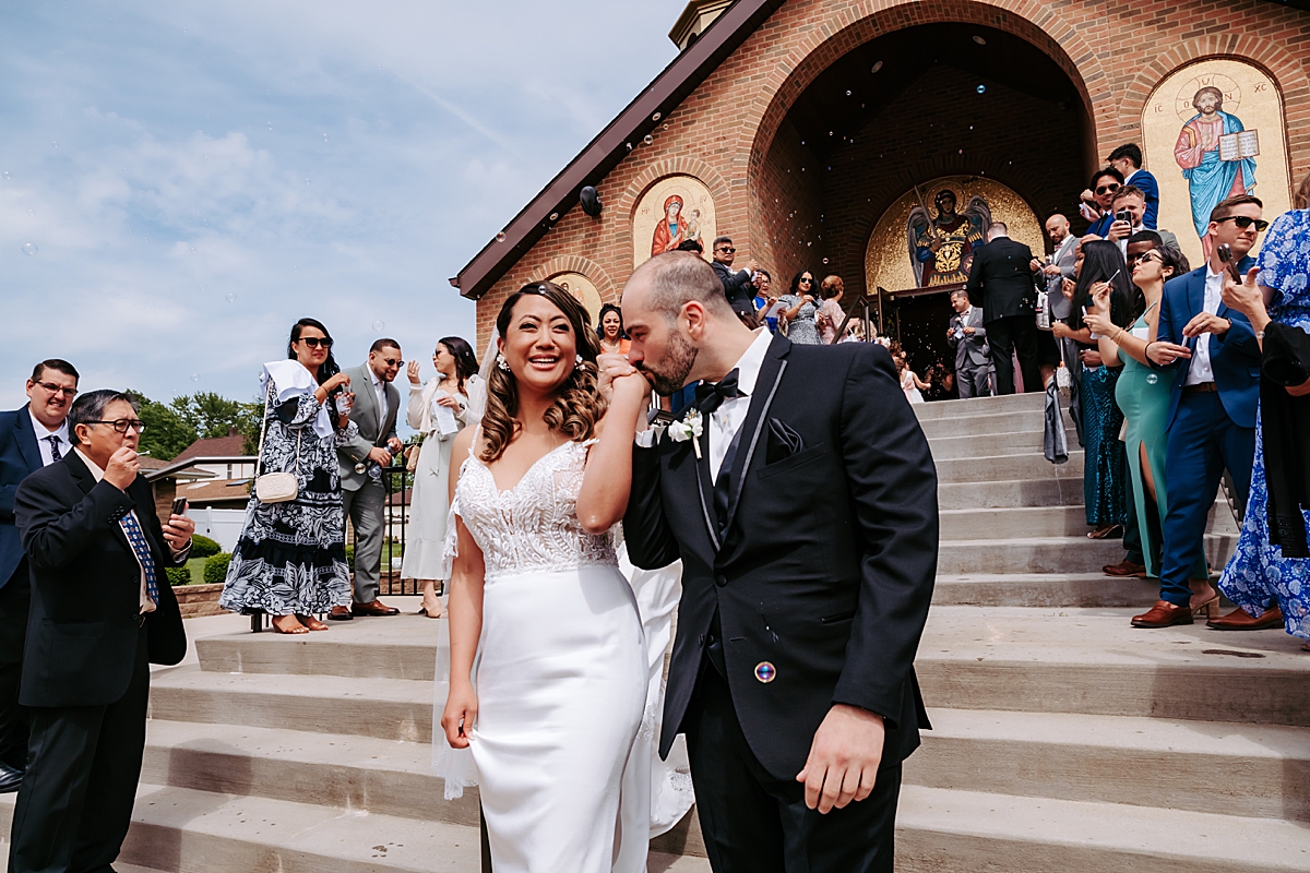 bride and groom walking down steps of Archangel Michael Greek Orthodox Church in Campbell OH