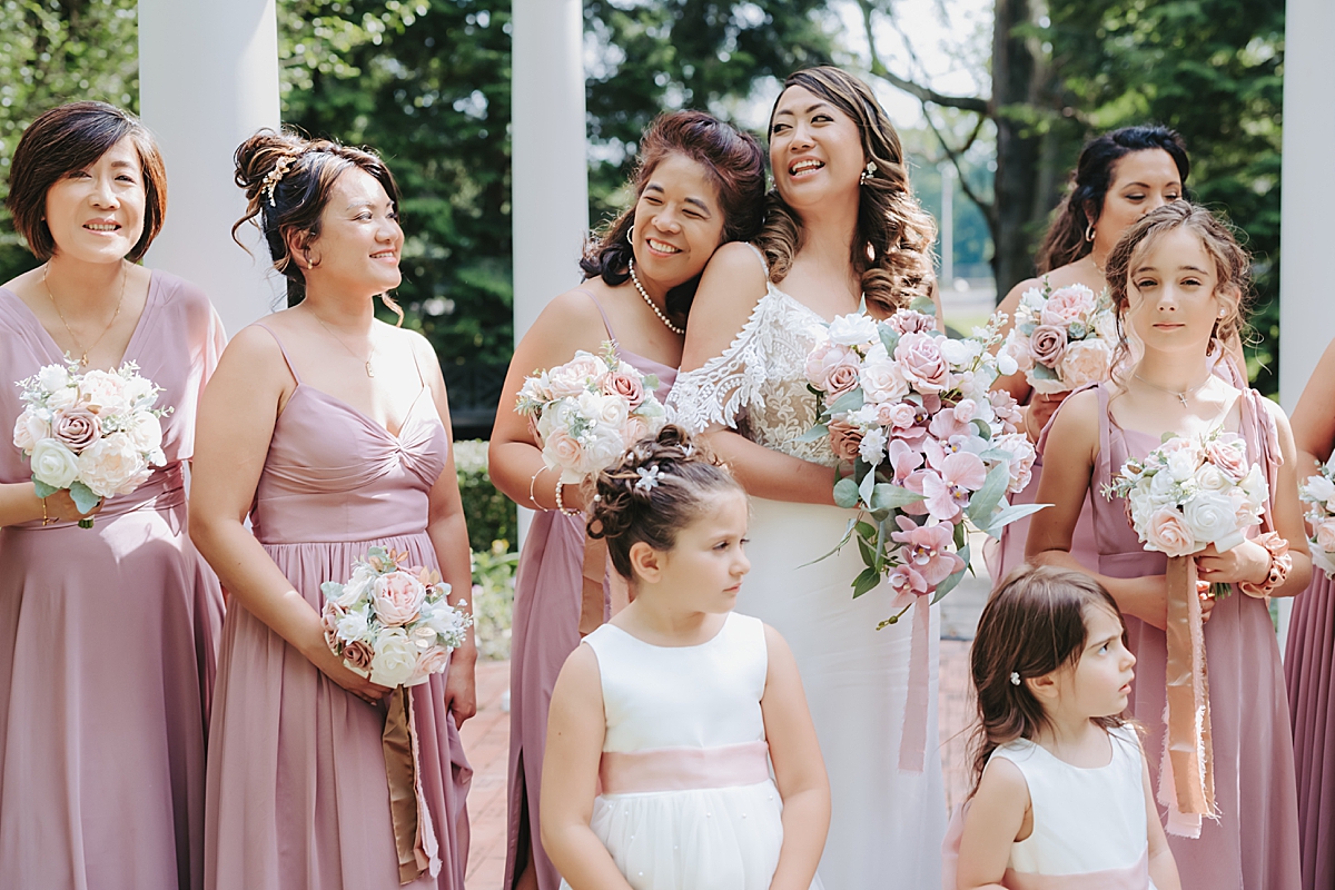 bride laughing with bridesmaids wearing dusty rose gowns