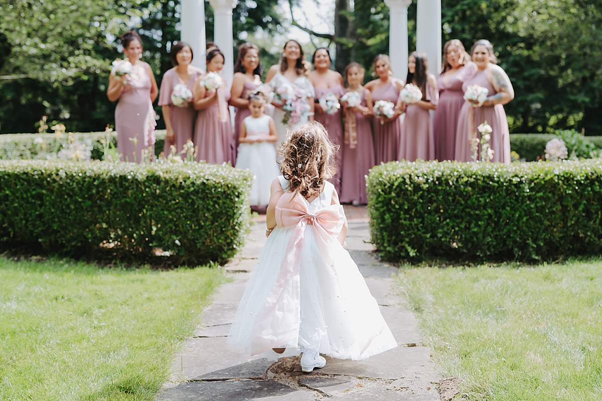 flower girl wearing white dress with pink bow on the back 