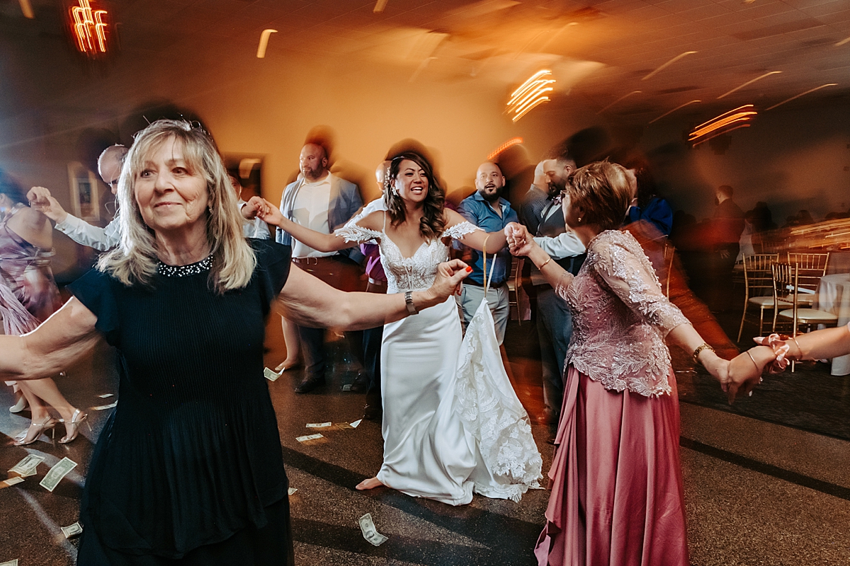 greek dancing at wedding with dollar bills on the ground