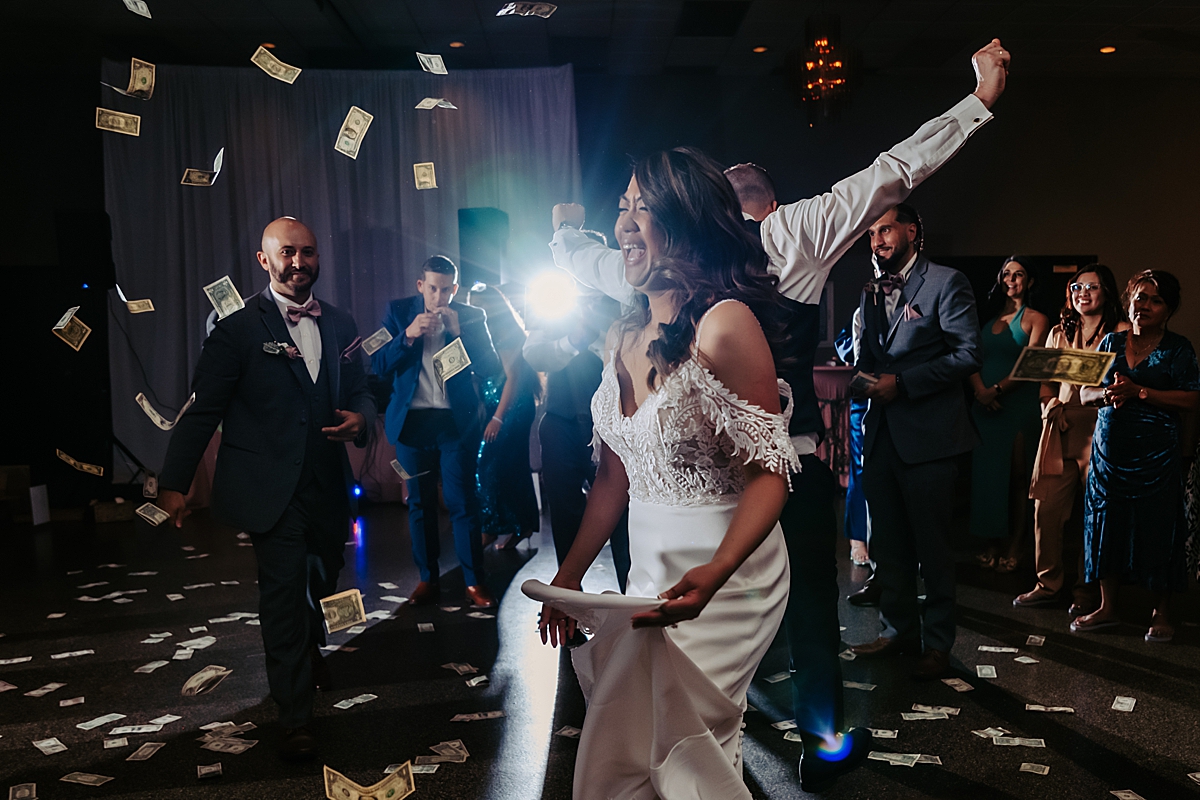 bride laughing and dancing with money thrown in the air