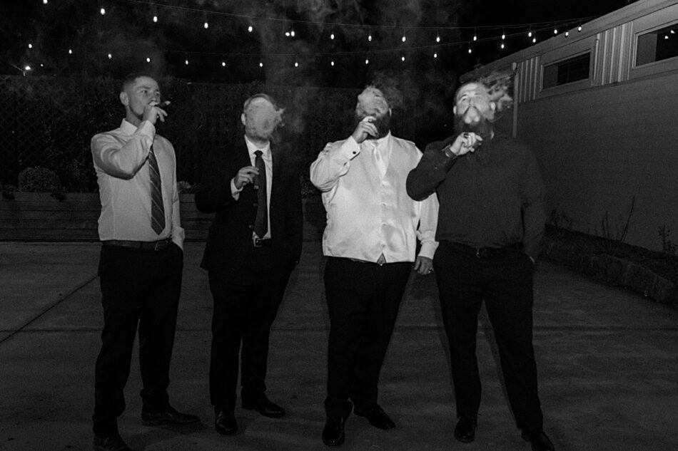 gentlemen standing outside during wedding reception smoking cigars