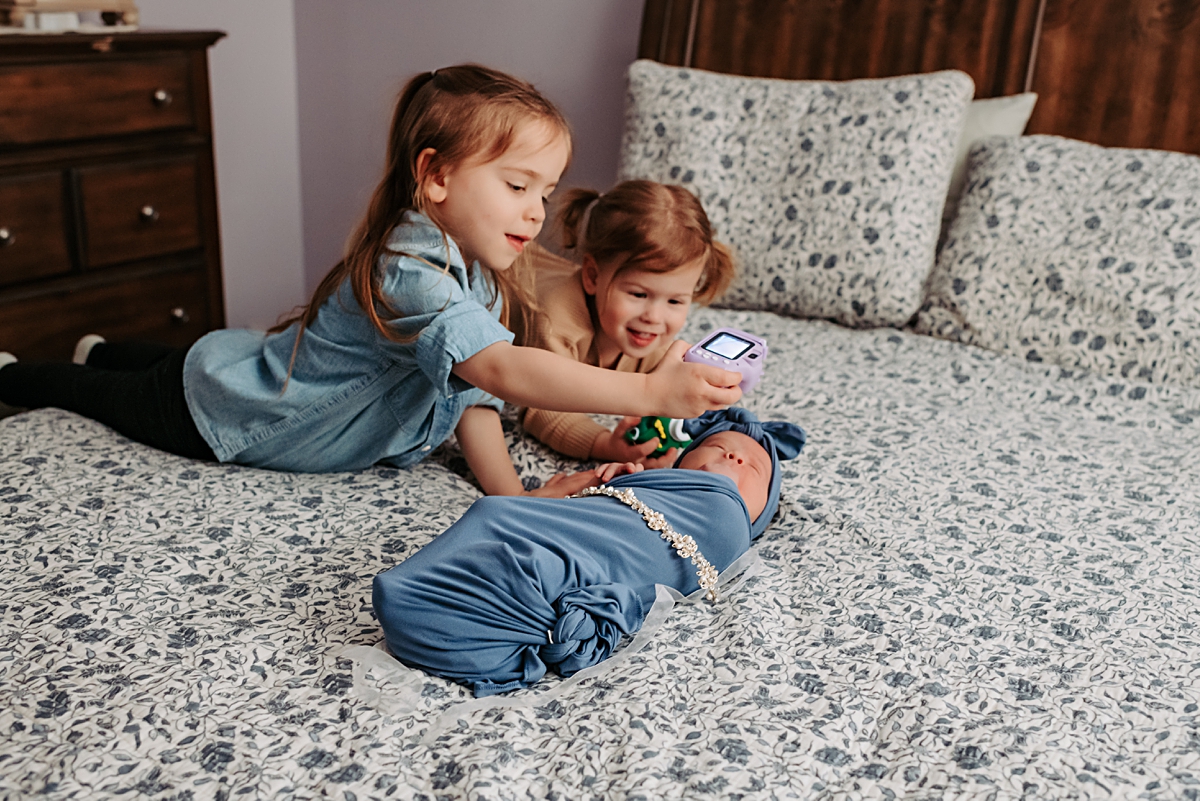 young girls taking photos of their newborn baby sister with their own camera