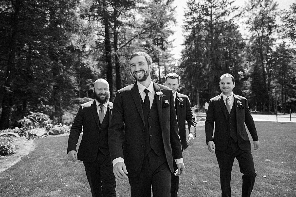 groom walking with groomsmen behind him laughing and smiling